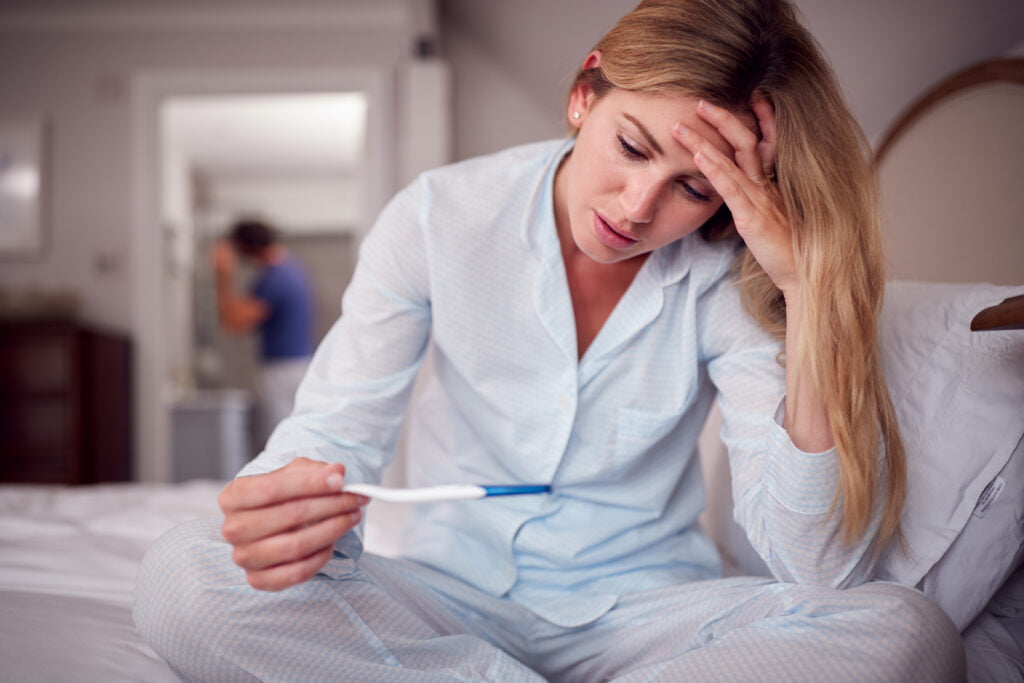 unhappy woman wearing pyjamas in bedroom holding p 6GM3EKC