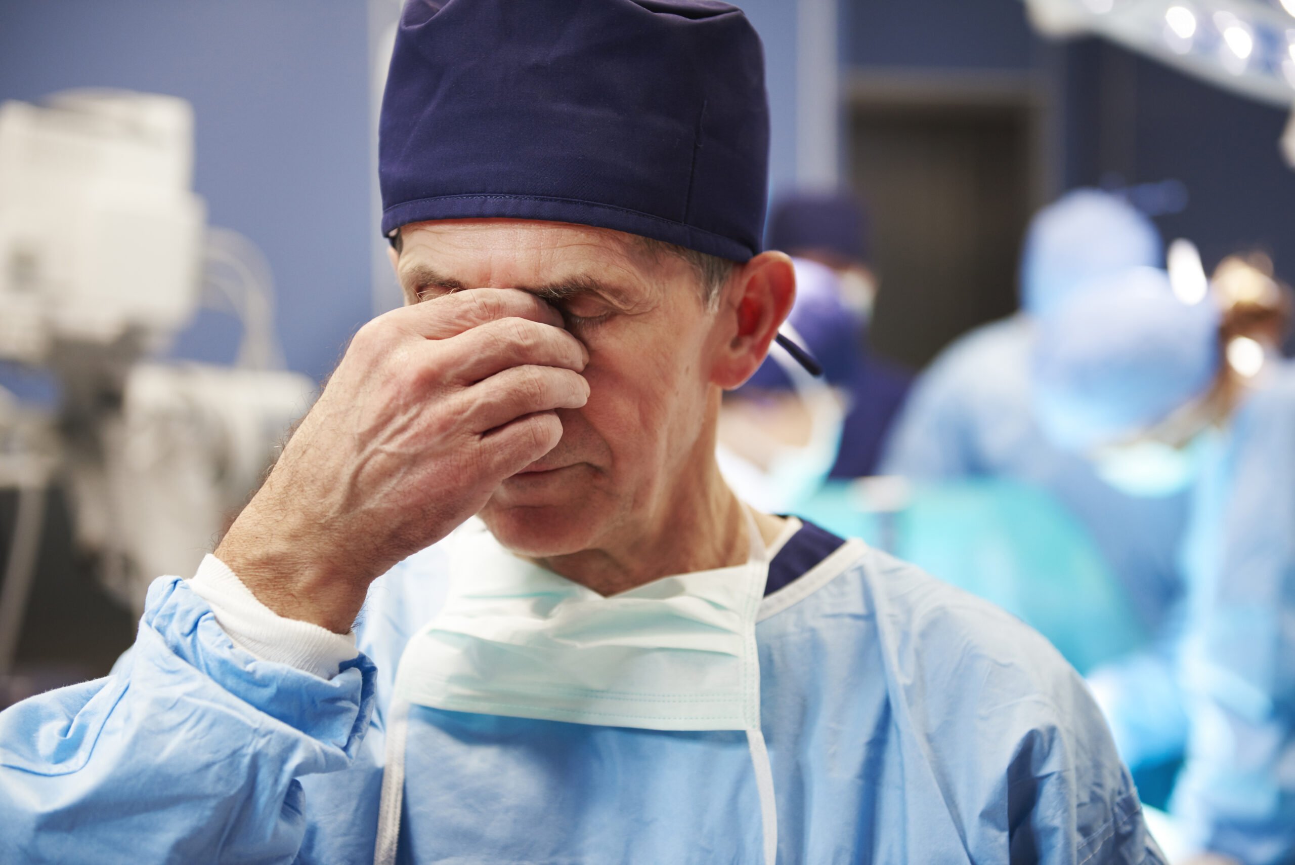 tired male doctor suffering from headache EX6BETA scaled